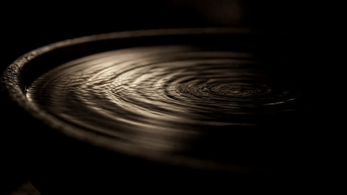 Ripples spreading across a dark reflective surface.
